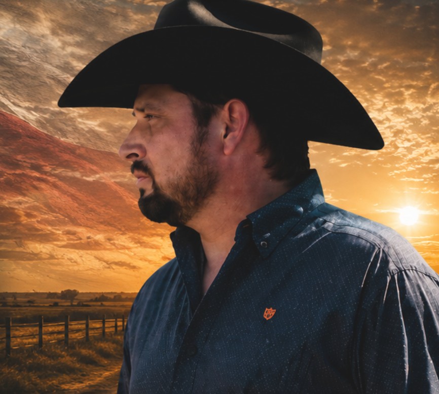 Wes Ryan in a black cowboy hat and blue shirt against a Texas sunset